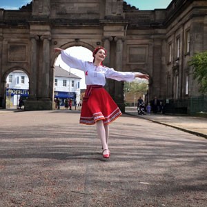Woman in an red and white ethnic costume dancing in an English square